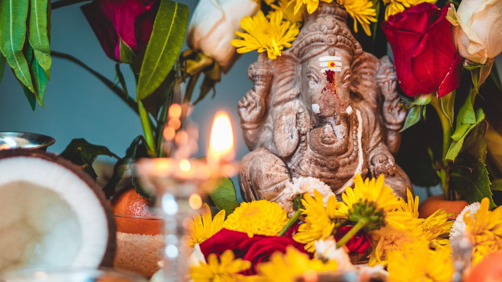Statue de Ganesha ornée de fleurs vibrantes et bougie allumée