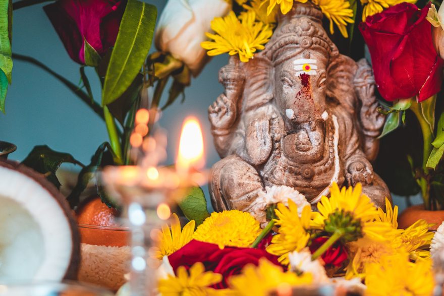 Statue de Ganesha ornée de fleurs vibrantes et bougie allumée