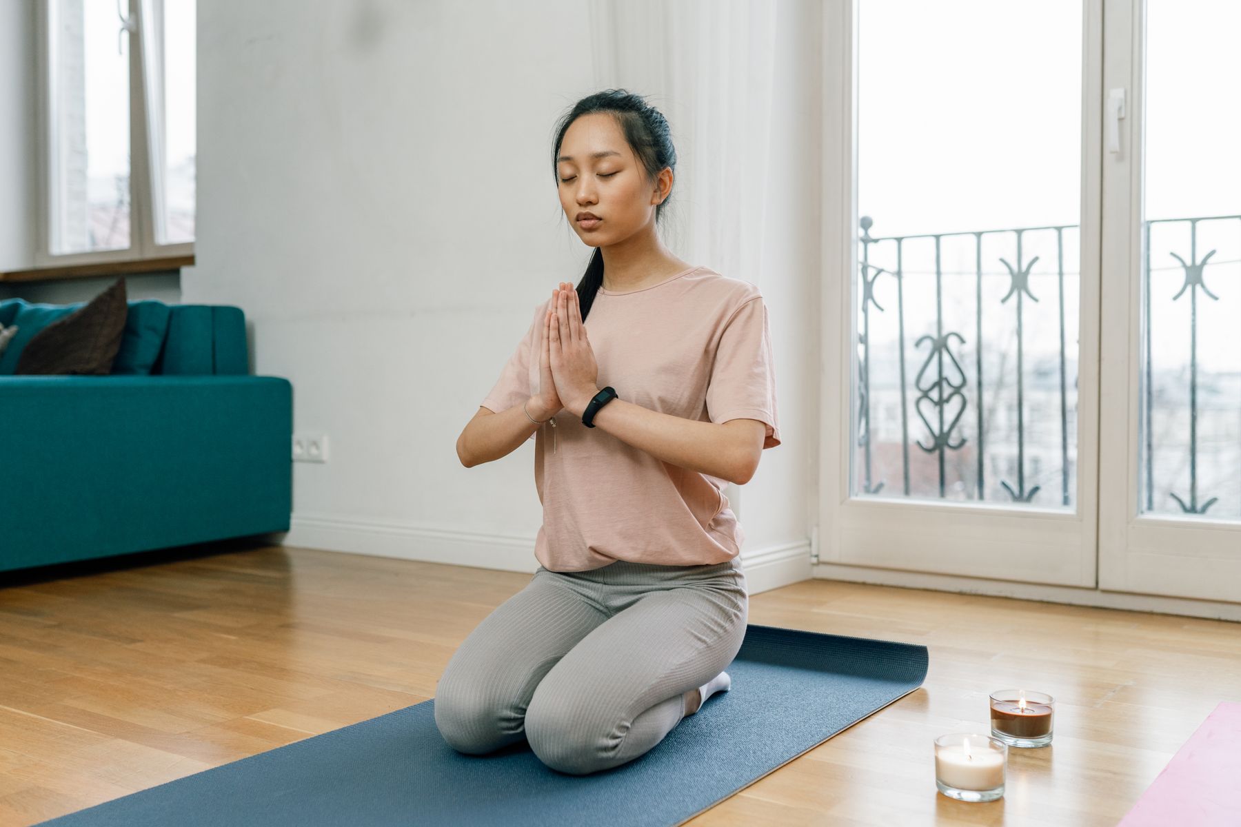Femme en position de méditation sur tapis bleu dans intérieur lumineux