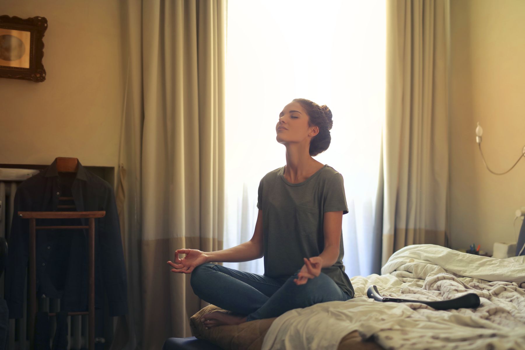 Femme en méditation sur lit baignée de lumière dorée naturelle