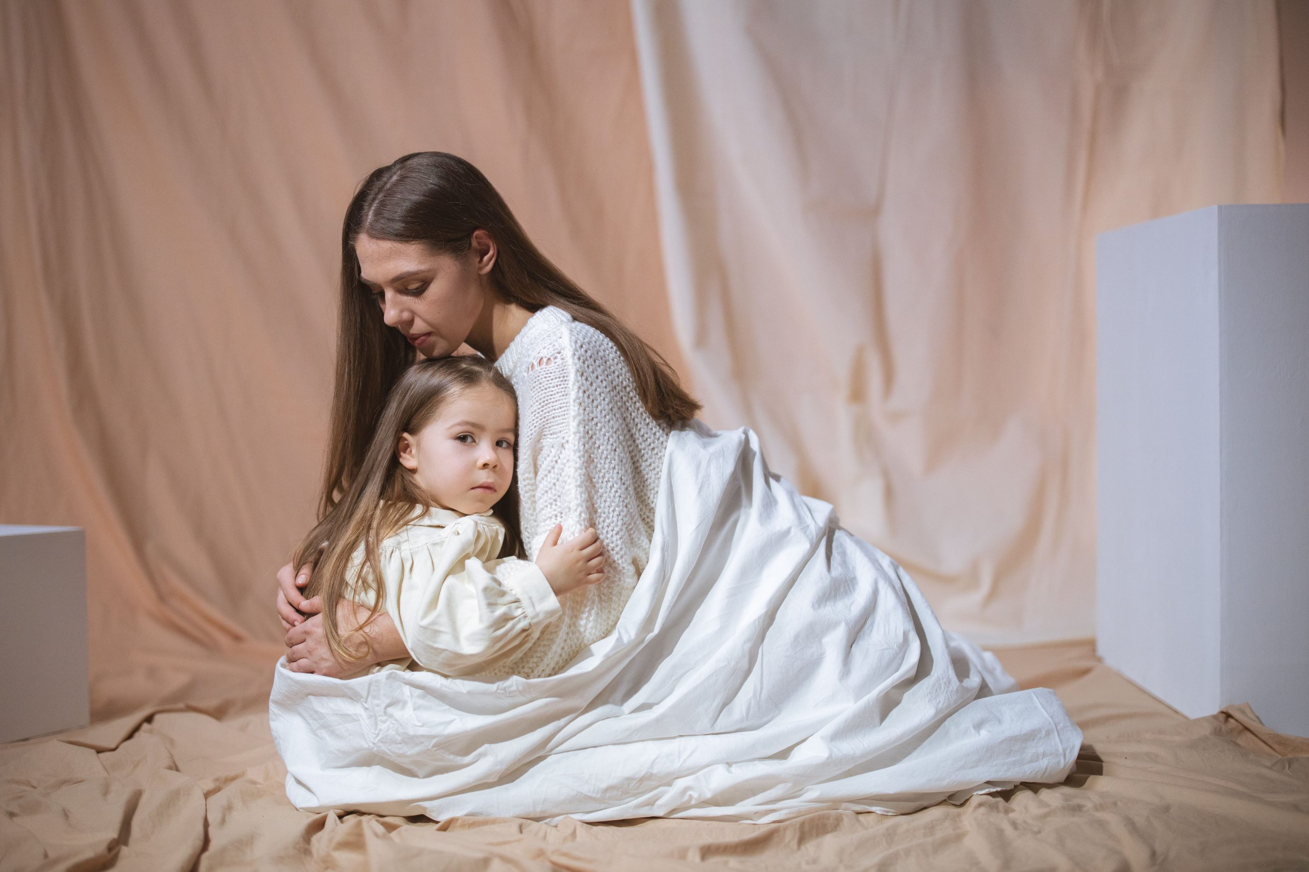 Mère et enfant enlacés sous une couverture blanche
