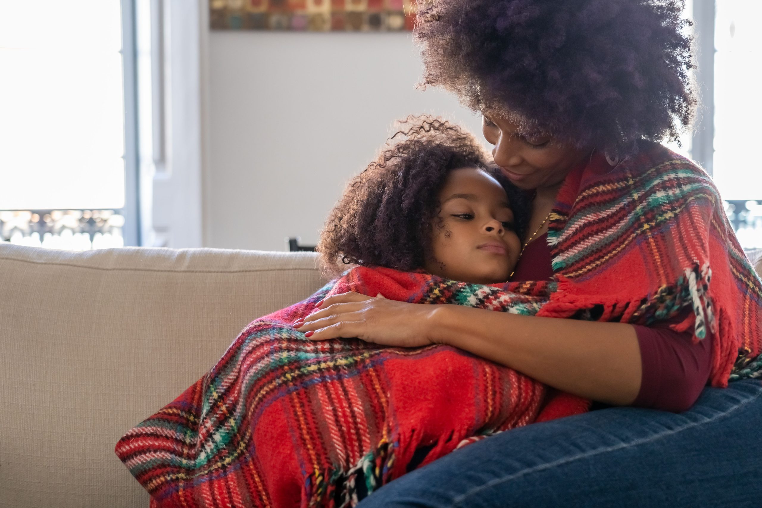 Mère embrassant son enfant sur un canapé confortable